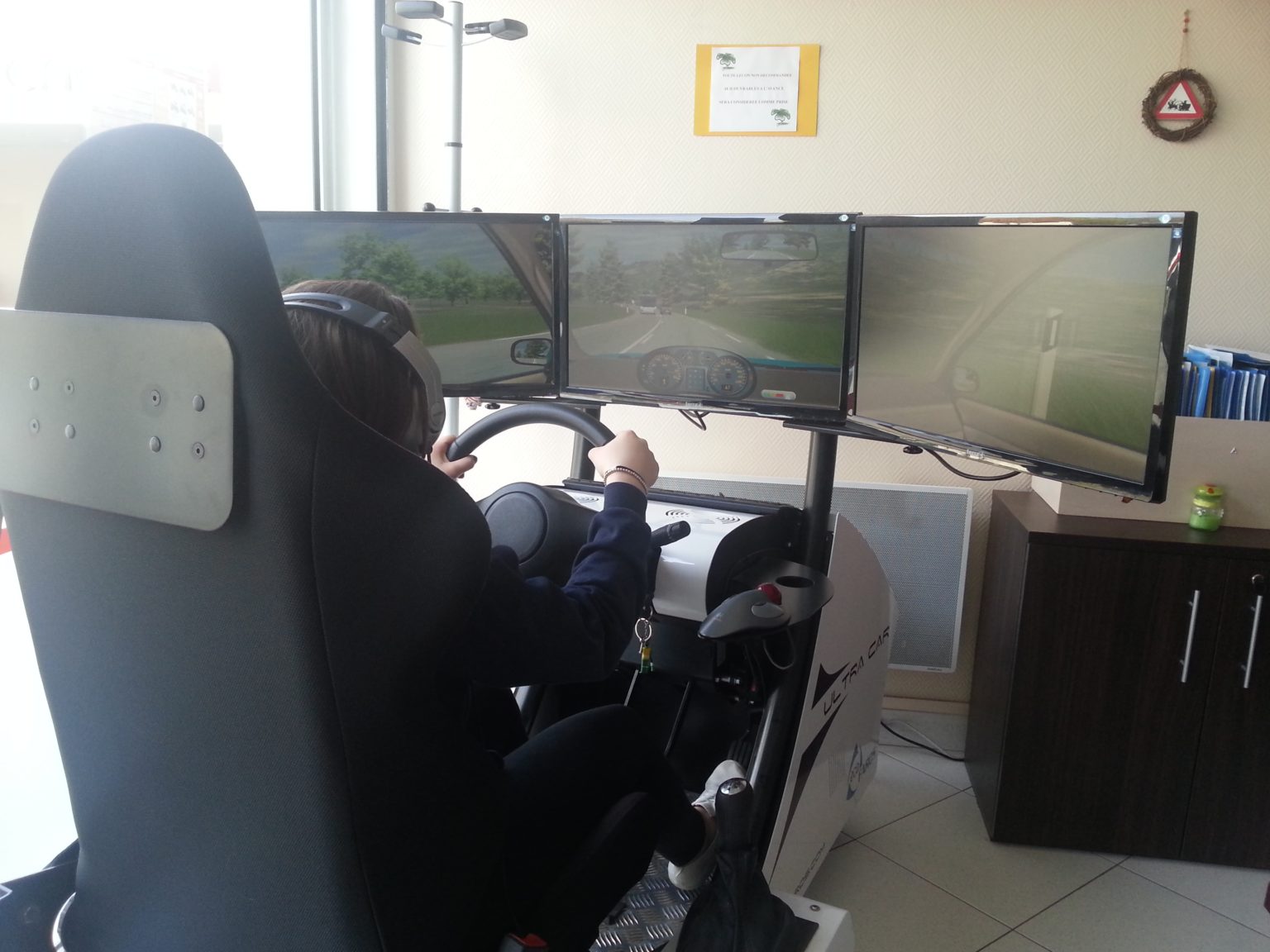 Élève au poste de conduite du simulateur, dans une agence de l'Auto-Moto-École Le Trèfle